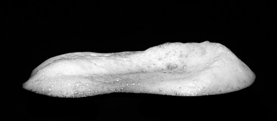 Liquid white foam from soap, shampoo or bath foam. Abstract soap bubbles. Set of soap bubbles. Separated soap bubbles on a textured and contrasting black background.	
