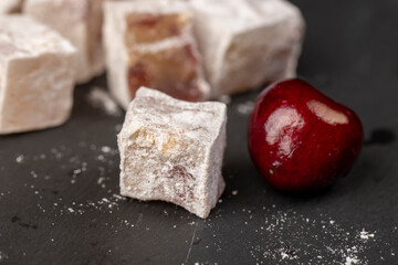 Turkish delight with cherry , cubes of Turkish delight with the addition of dried red berries in powdered sugar close up, side view