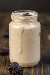 fresh yogurt with prune flavor with dried plum slices, jar with natural prune yogurt closeup