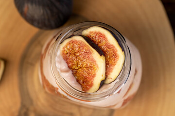 glass jar with fresh yogurt with ripe fresh figs, fresh pink yogurt with fig flavor in a glass jar and with figs cut into pieces, top view