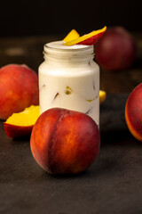 yogurt and peaches cut into pieces on slate, fermented milk product with peach flavor with the addition of pieces of peach
