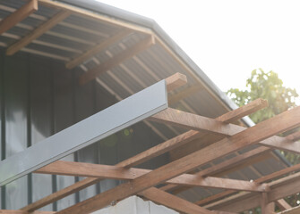 Gray eaves installation at end of rafter. Roof structure construction for house building. Wood member erecting to frame structure in gable shape.