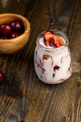 yogurt with cherry flavor and berry slices, glass jar with cherry yogurt with fresh red cherries closeup