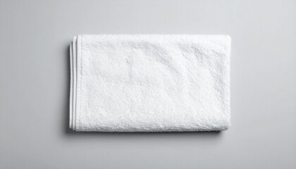 A neatly folded white towel on a light gray surface, showcasing its soft texture and clean appearance
