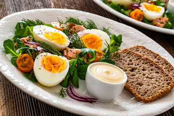Salmon appetizer - cold smoked salmon, hard boiled eggs, leafy greens and mayonnaise with bread on...