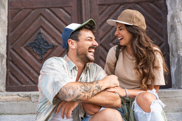 Young happy hipster millennial gen z couple in love and modern clothes sitting outdoor on the...