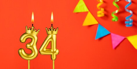 Number 34 birthday candle on an orange background with pennants
