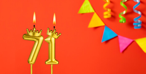 Number 71 candle - Birthday celebration on an orange background with pennants