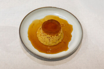 egg and milk flan on a white plate on a white tablecloth
