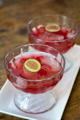 Red cold drink in glass with lemon slice on top