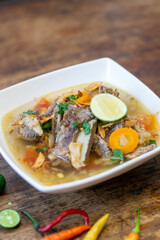 Close up of beef ribs and vegetables soup with lime on top