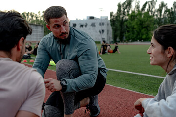Fitness instructor guiding athletes during training session on a running track, providing...
