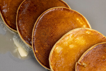 melting butter on freshly baked pancakes, several pancakes made from milk with flour on which...