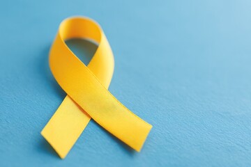 simple image of single yellow ribbon symbolizing hope and awareness against minimalist blue background