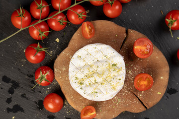 white soft cheese in salt and spices and small red round tomatoes on the table