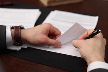 Notary signing document at wooden table, closeup