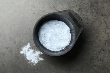 Bowl with hair bleaching powder on grey table, top view