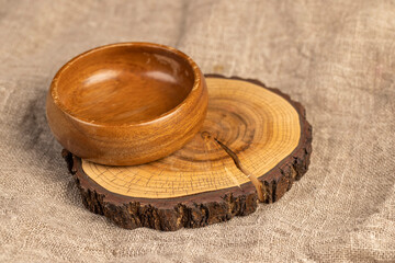 bowl on a stand on a linen tablecloth, an empty food bowl on the table is made of acacia wood