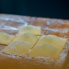 Raw uncooked ravioli on wooden cutting board