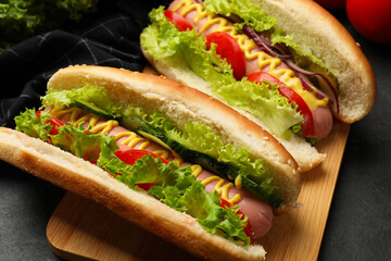 Tasty hot dogs with vegetables on black table, closeup