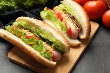 Tasty hot dogs with vegetables on black table, closeup