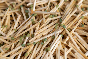 wooden matches with a green head scattered in a large pile, a large number of thin wooden matches with a green sulfur head, close up