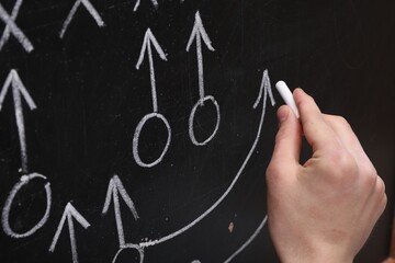 Man drawing American football game scheme on chalkboard, closeup