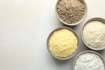 Different types of flour in bowls on light grey table, flat lay. Space for text