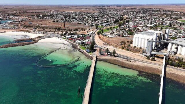 Drone flying over Wallaroo Jetty of York Peninsula with clear waters and city skyline on a sunny day