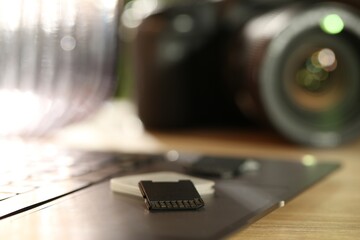 SD memory cards, holder, laptop and photo camera on wooden table, closeup