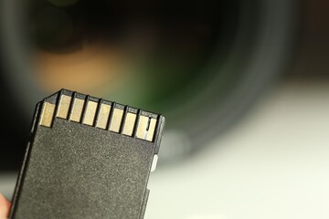 SD memory card on blurred background, closeup. Space for text