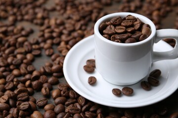 Aromatic coffee beans, cup and saucer on table, closeup. Space for text