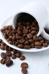 Aromatic coffee beans, cup and saucer on white table, closeup