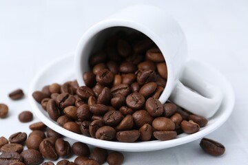 Aromatic coffee beans, cup and saucer on white table, closeup