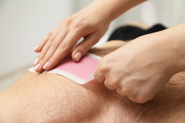 Young man undergoing wax epilation in salon, closeup