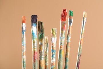 Dirty paintbrushes on light brown background, closeup