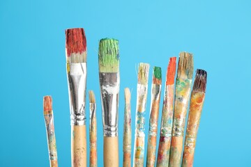 Dirty paintbrushes on light blue background, closeup