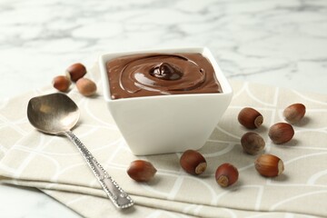 Tasty chocolate spread and hazelnuts on table, closeup