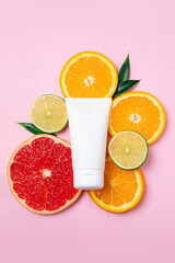 A minimalist skincare product surrounded by vibrant citrus fruits, including orange and grapefruit slices, on a pastel pink background. Perfect for beauty and freshness themes.