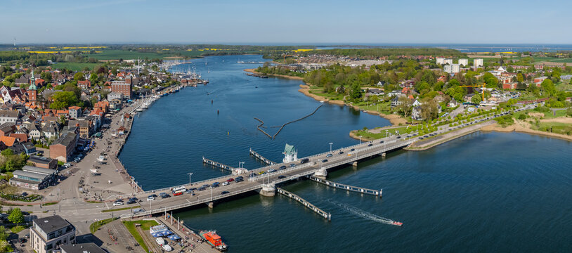 Aerial footage of Kappeln on Schlei fjord with historic old town, harbor and bridge with flowing traffic, all surrounded by spring landscape of Schleswig-Holstein, Germany.