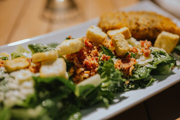 Caesar salad with croutons and bacon served outdoors in sunlight, summer salad styling concept 
