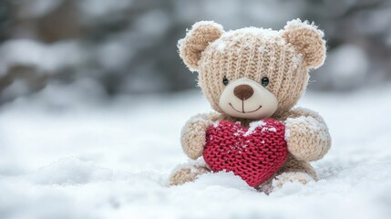 Cute teddy bear holds red heart, sitting in fresh white winter snow. Perfect for Valentines Day, love, or other heartfelt winter holiday.