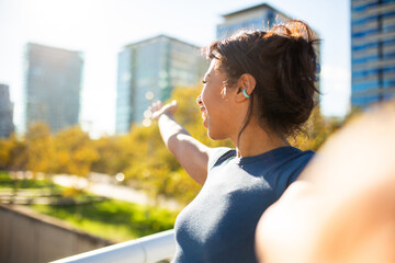 young woman smiling and pointing toward the city skyline while taking selfie