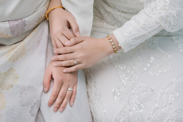 Close up hand muslim bride waering wedding ring on the left ring finger while holding the groom's hand with copy space. Concept for wedding card background, poster, invitation card.