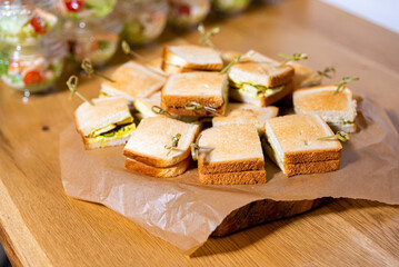 Mini toasted sandwiches on wooden serving tray.