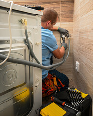 Professional plumber connecting water supply hose to washing machine in bathroom, ensuring proper...