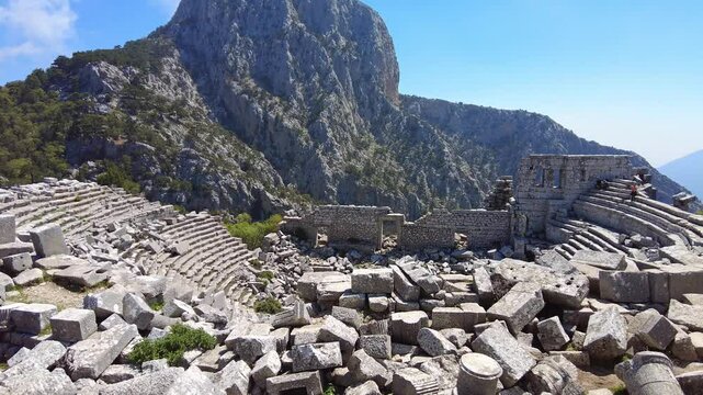 4K Tourists discovering the impressive ruins of an ancient theater (amphitheater) in Termessos, Turkey. Visitors take in the beauty of this historic site high above the valleys