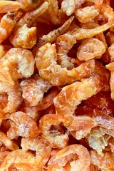 Close-up of dried shrimp. Small, pinkish-orange in color, they appear slightly translucent when cooked. Dried shrimp are often used as a seasoning or ingredient in various Asian dishes, adding a salty
