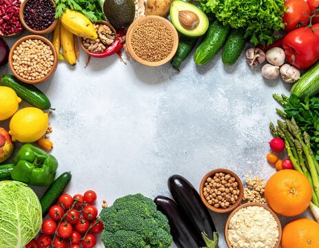 A vibrant circle of assorted fruits and vegetables, featuring bright red tomatoes, leafy greens, yellow bell peppers, and ripe bananas, all artfully arranged.