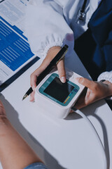 Nurse measuring blood pressure of elderly woman at table, closeup. Assisting senior generation